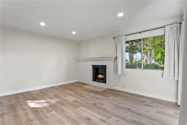 unfurnished living room with a fireplace and light wood-type flooring