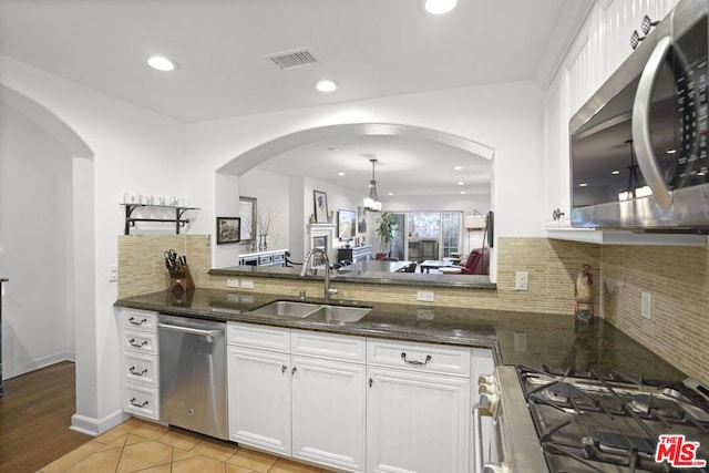 kitchen featuring pendant lighting, sink, white cabinets, dark stone counters, and stainless steel appliances