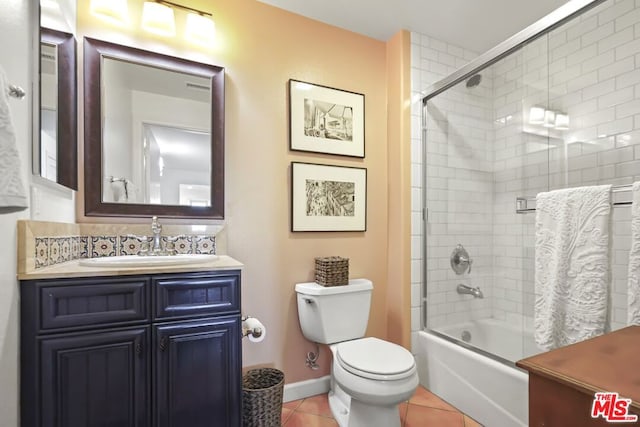 full bathroom featuring vanity, toilet, tile patterned flooring, and combined bath / shower with glass door