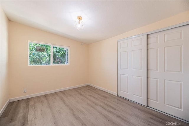 unfurnished bedroom with a closet and light wood-type flooring