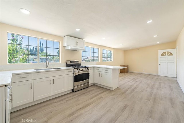 kitchen with sink, white cabinetry, stainless steel range with gas stovetop, kitchen peninsula, and light wood-type flooring