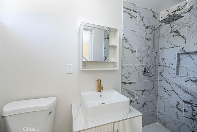 bathroom with vanity, tiled shower, and toilet