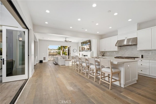 kitchen featuring white cabinetry, a kitchen bar, decorative backsplash, and a center island with sink