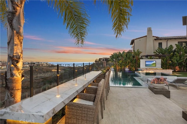 view of swimming pool featuring a bar, a patio, and an in ground hot tub