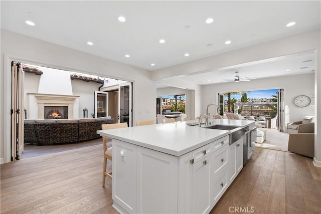 kitchen featuring white cabinetry, sink, light hardwood / wood-style floors, and an island with sink