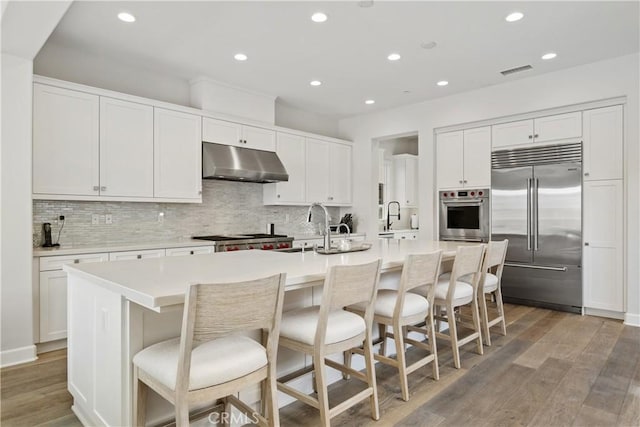 kitchen featuring an island with sink, appliances with stainless steel finishes, sink, and white cabinets