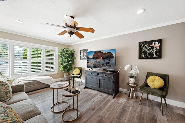 living room featuring light hardwood / wood-style flooring, ornamental molding, and ceiling fan