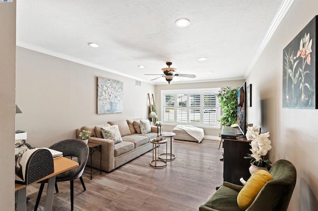 living room with crown molding, ceiling fan, a textured ceiling, and light wood-type flooring