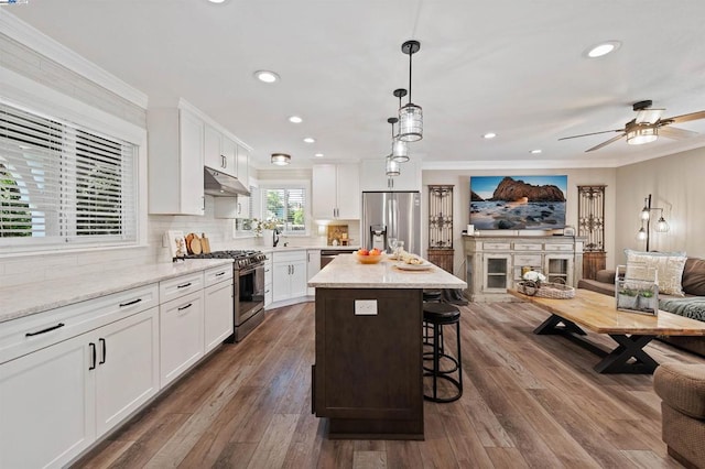 kitchen with hanging light fixtures, a kitchen island, white cabinets, and appliances with stainless steel finishes