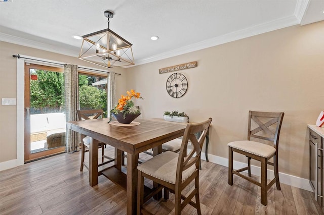 dining area featuring an inviting chandelier, ornamental molding, and hardwood / wood-style floors