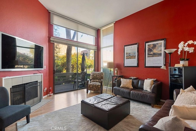 living room with a tile fireplace, floor to ceiling windows, and light hardwood / wood-style floors