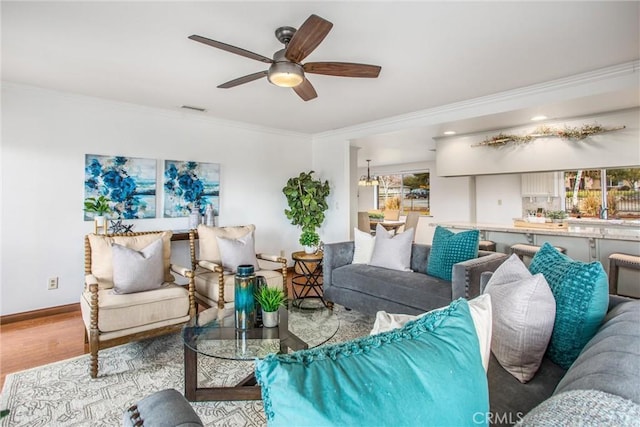 living room featuring ornamental molding, ceiling fan, and light wood-type flooring