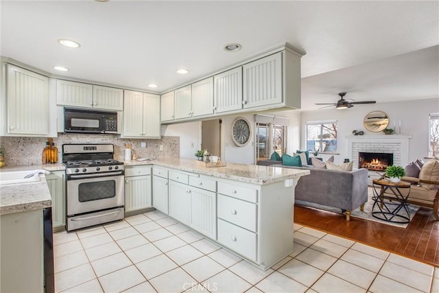 kitchen with light tile patterned floors, backsplash, a fireplace, gas range, and kitchen peninsula