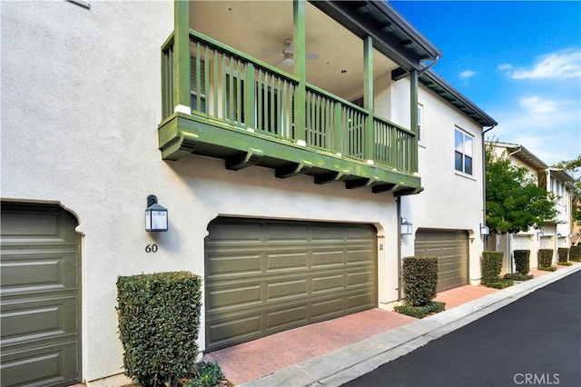 view of property exterior with stucco siding, a garage, and a balcony