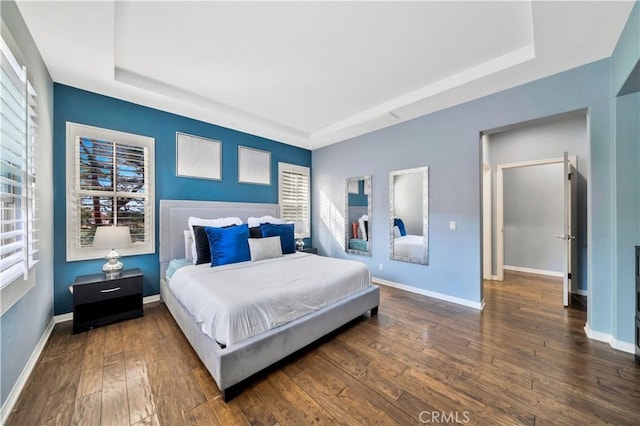 bedroom with baseboards, a raised ceiling, and hardwood / wood-style floors