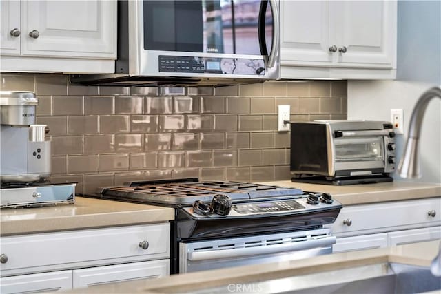 kitchen with backsplash, white cabinetry, appliances with stainless steel finishes, a toaster, and light countertops