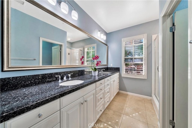 full bath featuring tile patterned floors, a sink, a shower stall, double vanity, and baseboards