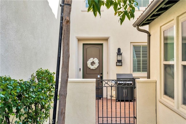 doorway to property featuring a gate, fence, and stucco siding