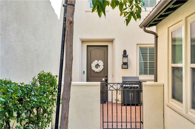 60 Peony, Irvine, CA 92618 - view of exterior entry with stucco siding, a gate, and fence