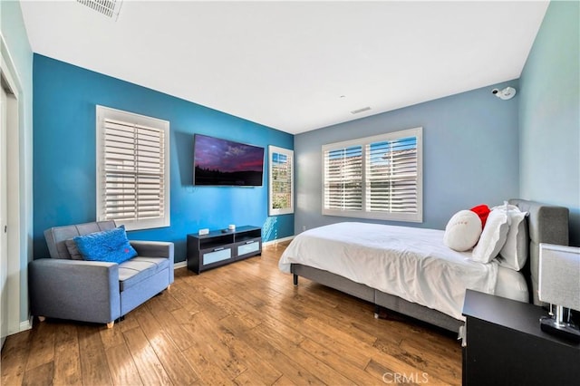 bedroom featuring baseboards, visible vents, and wood-type flooring