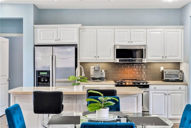 60 Peony, Irvine, CA 92618 - kitchen featuring stainless steel appliances, white cabinets, backsplash, a kitchen island with sink, and light countertops