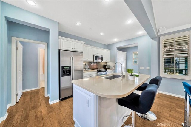 60 Peony, Irvine, CA 92618 - kitchen with stainless steel appliances, a sink, a breakfast bar area, light wood-style floors, and white cabinetry