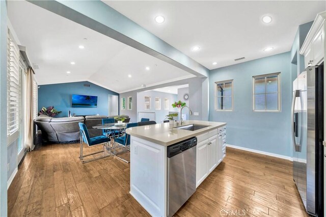 60 Peony, Irvine, CA 92618 - kitchen with stainless steel appliances, a sink, white cabinetry, hardwood / wood-style floors, and a kitchen island with sink
