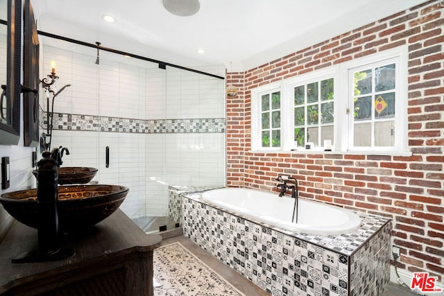 bathroom with brick wall, shower with separate bathtub, sink, and tile walls