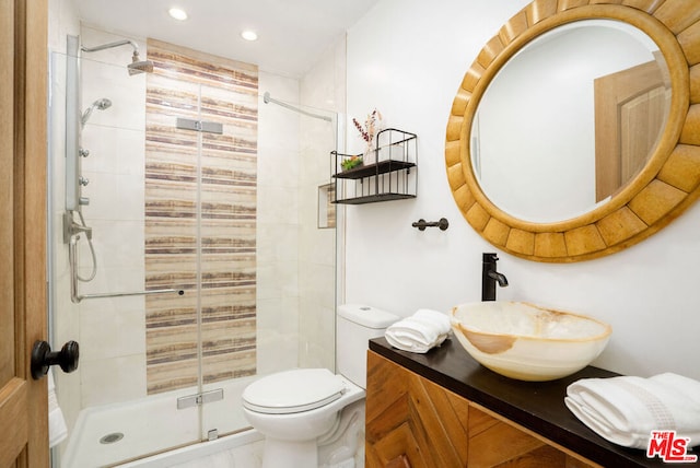 bathroom featuring a shower with door, vanity, and toilet