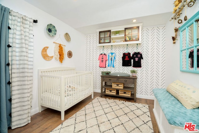 bedroom with hardwood / wood-style floors and a nursery area