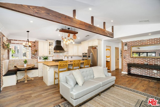 living room featuring crown molding, light hardwood / wood-style flooring, vaulted ceiling with beams, brick wall, and a chandelier