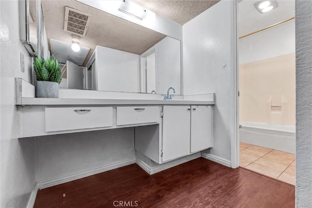 bathroom featuring vanity, tub / shower combination, wood-type flooring, and a textured ceiling