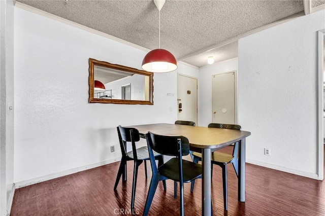 dining room with dark wood-type flooring, ornamental molding, and a textured ceiling