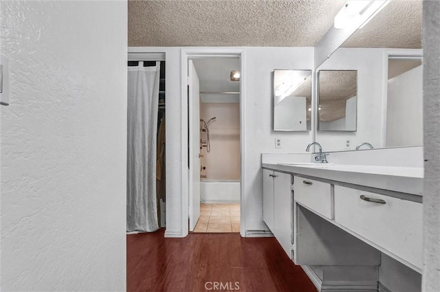 bathroom featuring wood-type flooring, tub / shower combination, vanity, and a textured ceiling