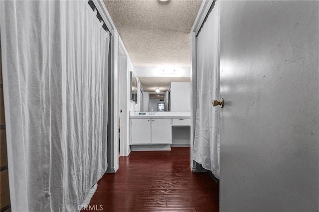 hall featuring sink, dark hardwood / wood-style floors, and a textured ceiling