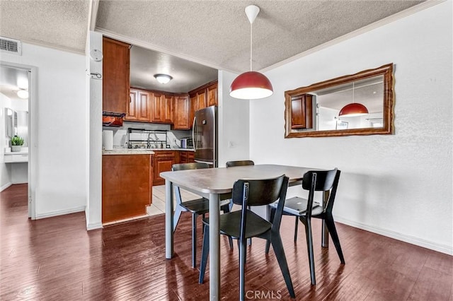 dining area featuring ornamental molding, dark hardwood / wood-style flooring, and a textured ceiling