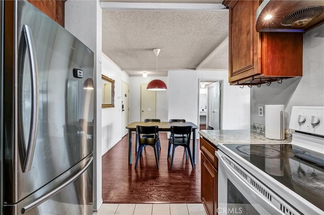 kitchen featuring white electric range, extractor fan, light stone counters, a textured ceiling, and stainless steel refrigerator