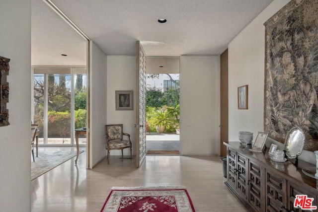 entryway featuring light hardwood / wood-style flooring, floor to ceiling windows, and a textured ceiling