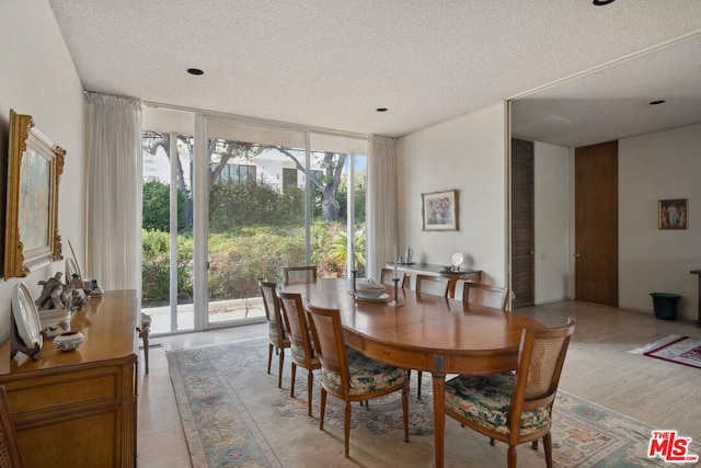 dining space featuring expansive windows, a textured ceiling, and light wood-type flooring