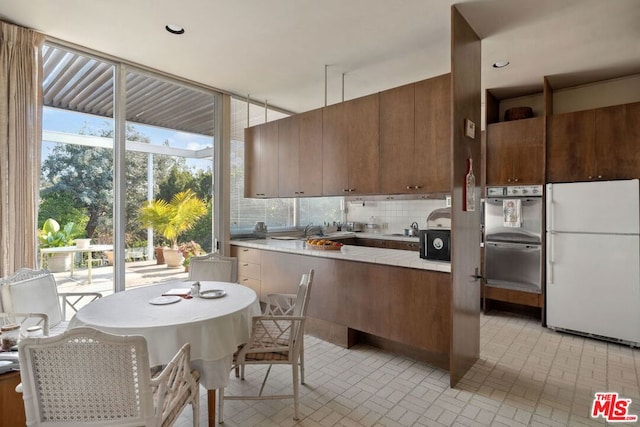 kitchen featuring tasteful backsplash, white fridge, and stainless steel oven