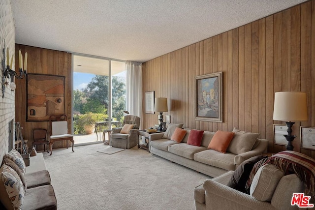 carpeted living room with wooden walls, a textured ceiling, a wall of windows, and a fireplace