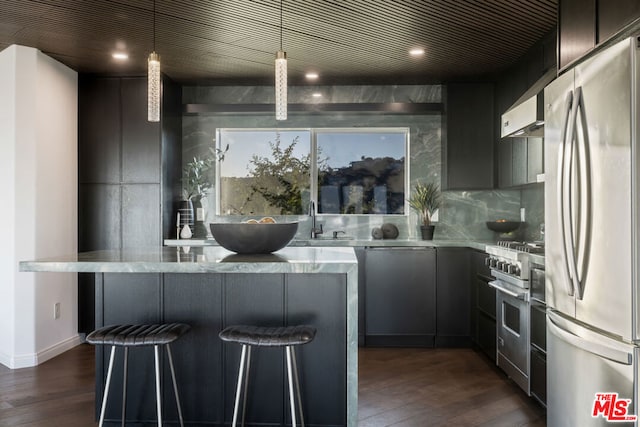 kitchen with dark wood-type flooring, stainless steel appliances, decorative light fixtures, and sink