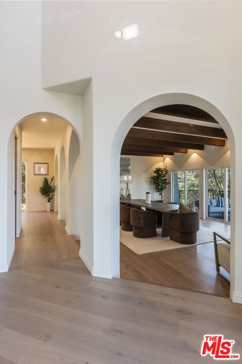 corridor featuring hardwood / wood-style flooring, a towering ceiling, and beam ceiling