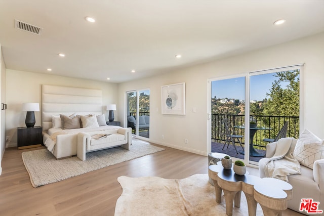 bedroom featuring multiple windows, access to outside, and light hardwood / wood-style floors