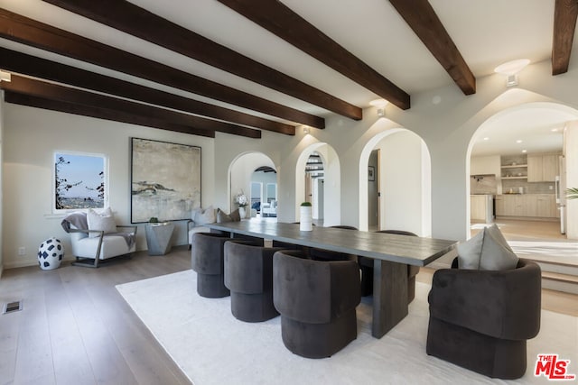 dining space with hardwood / wood-style flooring and beamed ceiling