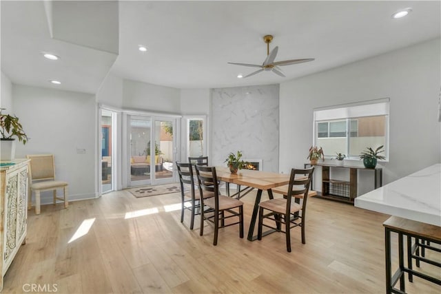 dining space featuring a fireplace, light hardwood / wood-style floors, and ceiling fan