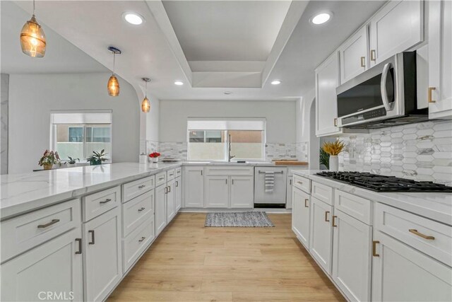 kitchen with white cabinetry, stainless steel appliances, light stone countertops, and hanging light fixtures