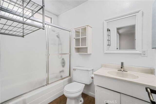 full bathroom featuring enclosed tub / shower combo, vanity, and toilet