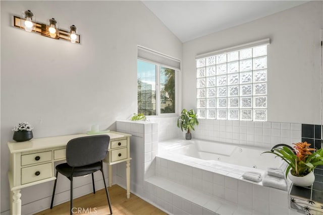 bathroom featuring tiled tub, hardwood / wood-style flooring, and vaulted ceiling