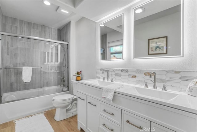 full bathroom with toilet, bath / shower combo with glass door, vanity, hardwood / wood-style floors, and decorative backsplash